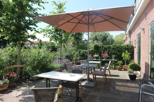 a patio with tables and chairs and an umbrella at B&B - Pension Het Oude Dorp in Katwijk