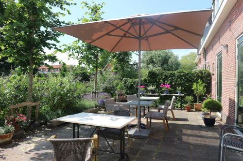 a patio table with chairs and umbrellas at B&B - Pension Het Oude Dorp in Katwijk