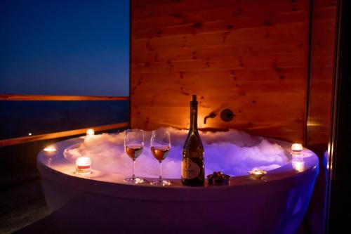 Uma garrafa de champanhe e dois copos de vinho num banho de espuma. em Rinari Spa House em Barič