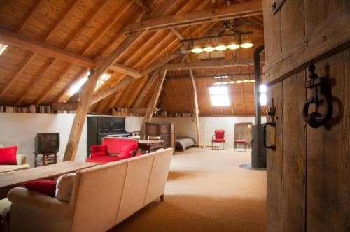 Großes Zimmer mit Sofas und einem Tisch in einer Scheune in der Unterkunft Chambre d'Hôtes des Grands Moulins de Baugé in Baugé