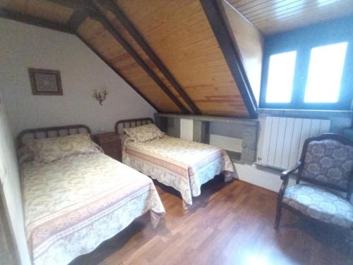 a attic bedroom with two beds and a chair at Apartamentos Sorripas 2 hab in Bielsa