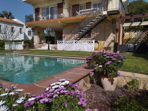 a house with a swimming pool and some flowers at Sunny Holiday Home in Creixell