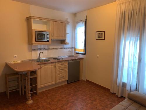 a kitchen with wooden cabinets and a sink and a window at Apartamento El Campanario in Zuheros