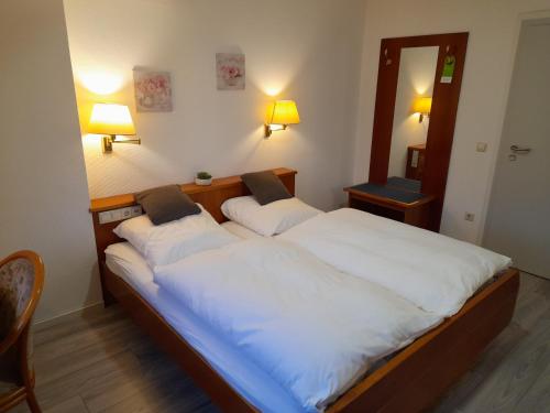 1 dormitorio con 1 cama grande con sábanas blancas en Hotel Zurmühlen, en Sendenhorst
