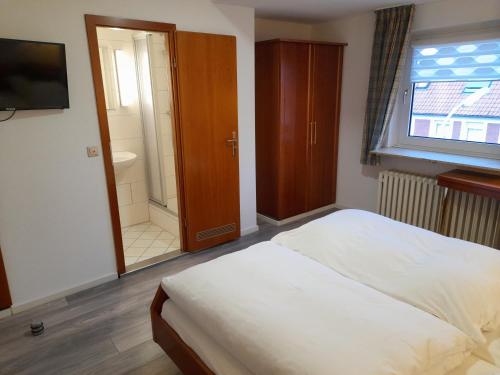 a bedroom with a bed and a bathroom with a shower at Hotel Zurmühlen in Sendenhorst