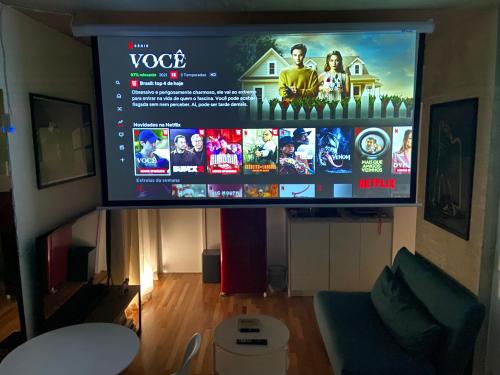 TV grande en la sala de estar con sofá en 85 New studio w balcony, fast wifi and movie screen!, en São Paulo