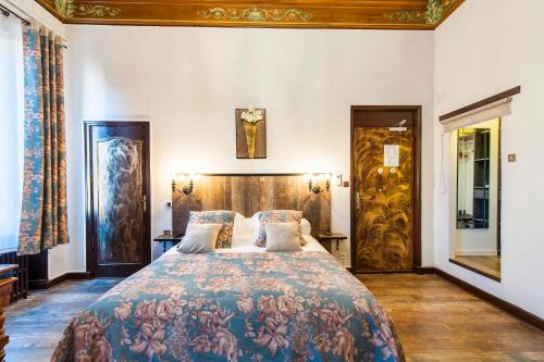 a bedroom with a large bed with a floral bedspread at Hôtel de Charme Le Provence in Salon-de-Provence