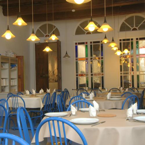 une salle à manger avec des tables, des chaises bleues et des lumières dans l'établissement Ethic étapes le Cart, à Sommières