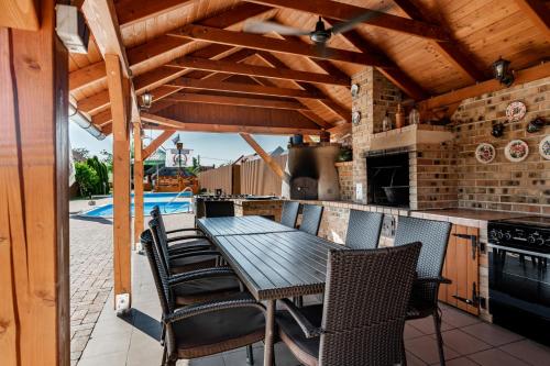 an outdoor kitchen with a wooden table and chairs at Bence Apartman in Tiszabábolna