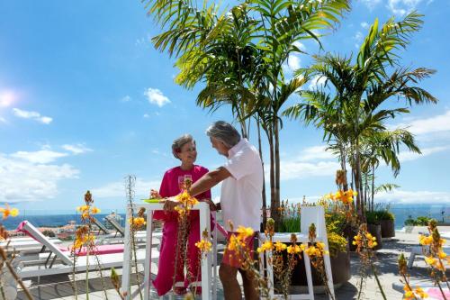 a man and woman standing next to a fence with flowers at Spring Hotel Bitácora in Playa de las Americas