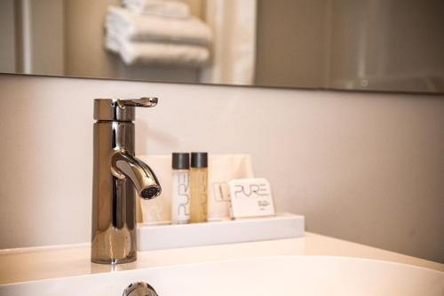 a bathroom sink with a faucet in front of a mirror at Hotel Les Trois Soeurs in Perce