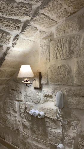 un mur en pierre avec une lampe et un téléphone dans l'établissement Le Vecchie Mura suite & room, à Manfredonia