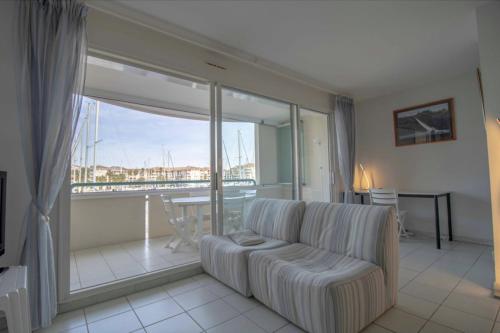 un salon avec un canapé et une grande fenêtre dans l'établissement Apartment With Balcony And View On The Port, à Fréjus