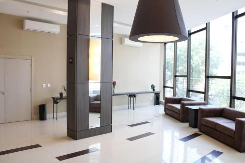 una sala de estar con sofás, mesas y ventanas en Flat 808 moderno e privilegiada localização no Centro, en Três Rios