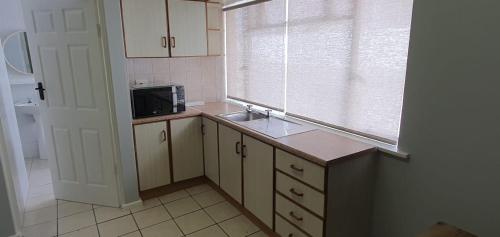 a small kitchen with a sink and a microwave at TinyApartment@Mosselbay - Entire 1 Bedroom Apartment Mossel Bay Central in Mossel Bay