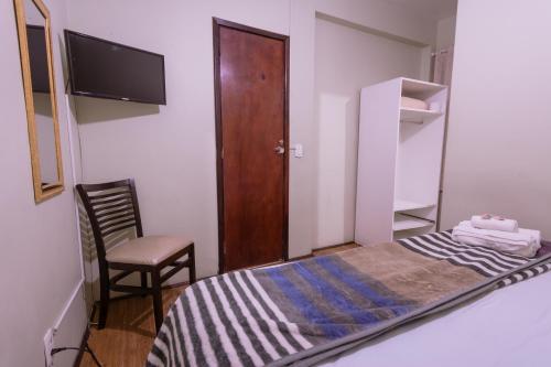 um pequeno quarto com uma cama e uma cadeira em Hotel Serra da Estrela em Petrópolis