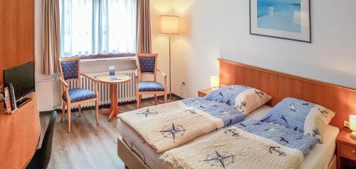 Cette chambre comprend 2 lits et une table. dans l'établissement Pension Haus Weierts, à Norderney