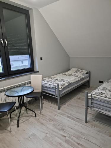 a room with two beds and a table and chairs at Noclegi 24/h Leszczynek in Kutno