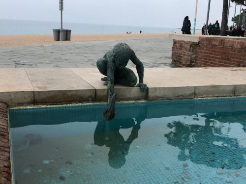 una estatua de un hombre en el borde de una piscina en Excepcional 1ª línea de mar Platja d'Aro Elypalace 10-2, en Platja d'Aro