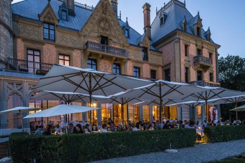 people sitting at tables under umbrellas in front of a building at Schloss Schadau - Swiss Historic Hotel in Thun