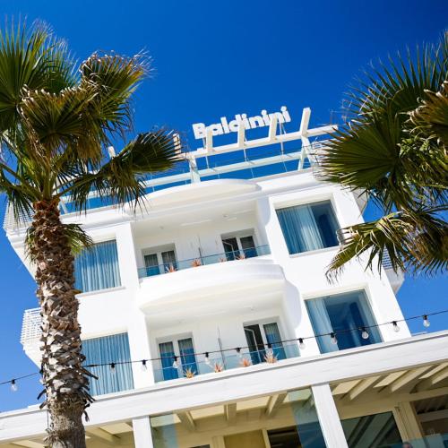 a white building with a palm tree in front of it at Baldinini Hotel in Rimini