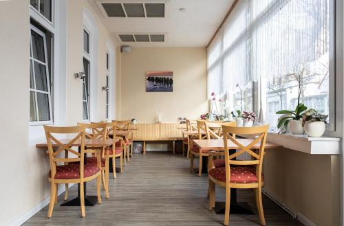 a restaurant with wooden tables and chairs and windows at Pension Haus Weierts in Norderney