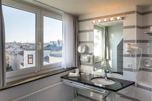 a bathroom with a sink and a mirror and a window at Holiday Inn Vienna City by IHG in Vienna