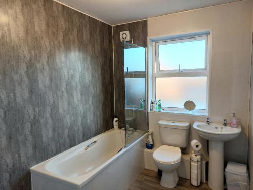 a bathroom with a tub sink and a toilet and a window at Edenderry Town House in Belfast