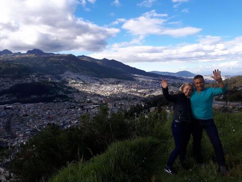a man and woman standing on a hill with their hands in the air at Häuschen nahe Cotopaxi-House near Cotopaxi in Machachi