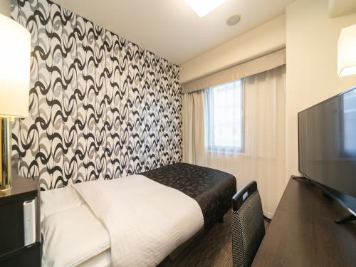a hotel room with a bed and a flat screen tv at APA Hotel Namba Kita Shinsaibashi Ekimae in Osaka