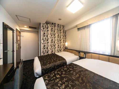大阪市にあるアパホテル〈なんば北 心斎橋駅前〉 のベッド2台と窓が備わるホテルルームです。