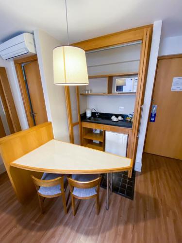 a room with a table and chairs and a kitchen at Transamerica Executive Faria Lima in Sao Paulo