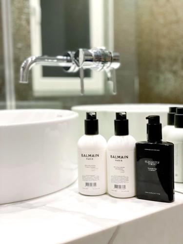 three shampoo bottles sitting on a bathroom counter in front of a sink at Selling Sunset Apartments in Timişoara
