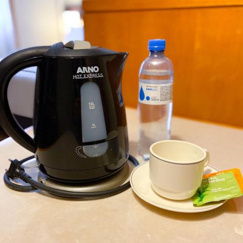 a coffee maker and a cup and a bottle of water at Transamerica Executive Faria Lima in Sao Paulo