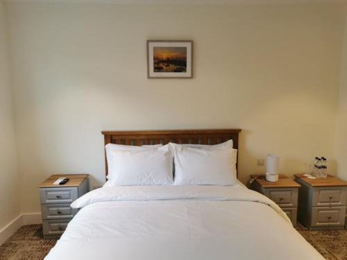 um quarto com uma cama branca com duas mesas de cabeceira em Coliemore Acommodation Dalkey em Dalkey