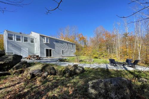 a modular home in the woods with two chairs at Spacious, Sunny Lake House! Close to ski trails. in Windsor