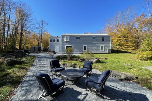 a group of chairs and a table in front of a house at Spacious, Sunny Lake House! Close to ski trails. in Windsor