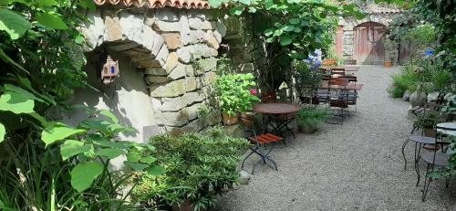 einen Garten mit Tischen und Stühlen und einer Steinmauer in der Unterkunft Schillers Stadthaus in Hitzacker