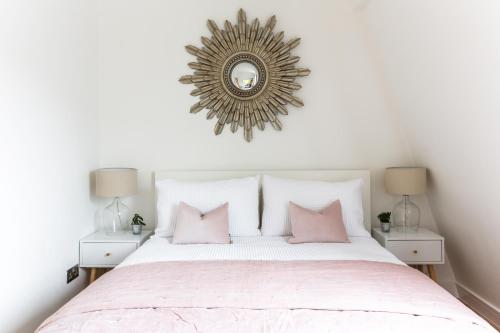um quarto com uma cama com almofadas cor-de-rosa e um espelho em The Penthouses, 9 Albion Mews em Chester