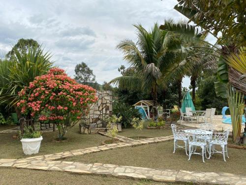 a garden with a table and chairs and flowers at Hospedagem Recanto das Orquideas in Quatis