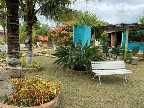a white bench in a garden with palm trees and plants at Hospedagem Recanto das Orquideas in Quatis