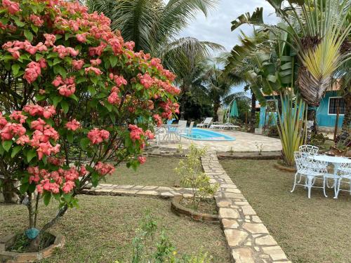 a garden with pink flowers and a swimming pool at Hospedagem Recanto das Orquideas in Quatis