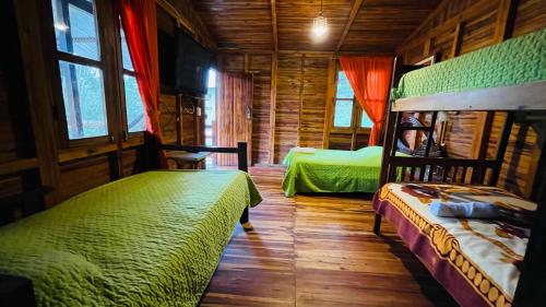 1 dormitorio con 2 camas en una cabaña de madera en Hostería Kasadasa, en Santo Domingo de los Colorados