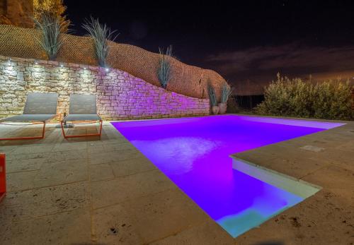 a swimming pool with purple lighting in a backyard at night at La Maison du Passage - Chambres - Suites premium, Spa, Piscine et Restaurant in Martignargues