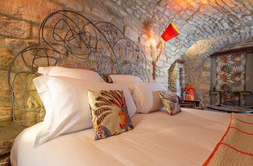 a bedroom with a bed in a stone wall at La Maison du Passage - Chambres - Suites premium, Spa, Piscine et Restaurant in Martignargues