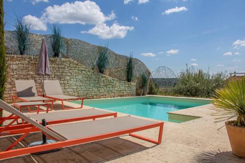 a swimming pool with two lounge chairs next to a stone wall at La Maison du Passage - Chambres - Suites premium, Spa, Piscine et Restaurant in Martignargues