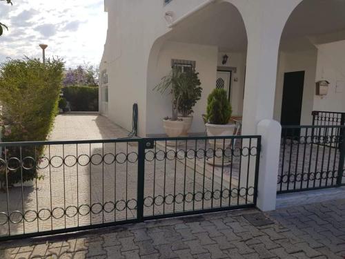 a black fence in front of a house with potted plants at Altura Beach House in Altura