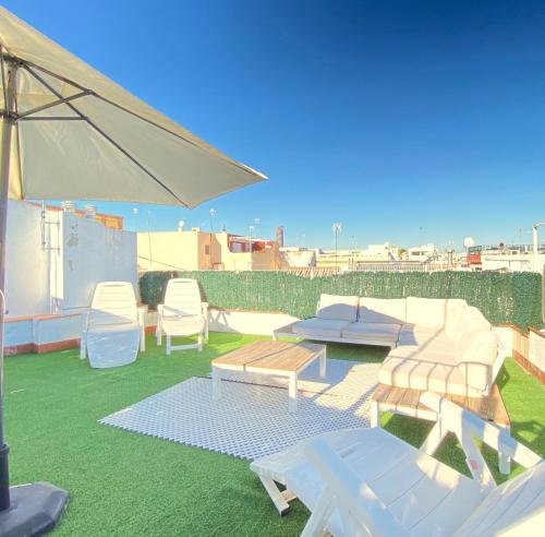 un patio con sillas, una mesa y una sombrilla en Top-notch downtown house with private rooftop terrace and parking opt en Sevilla