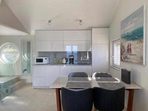 uma cozinha com armários brancos e uma mesa e cadeiras em Amazing villa Galeb in Murter em Murter