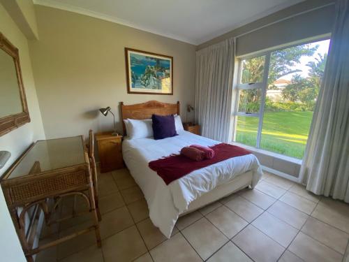 a bedroom with a bed and a large window at Goose Valley Unit EE4 in Plettenberg Bay